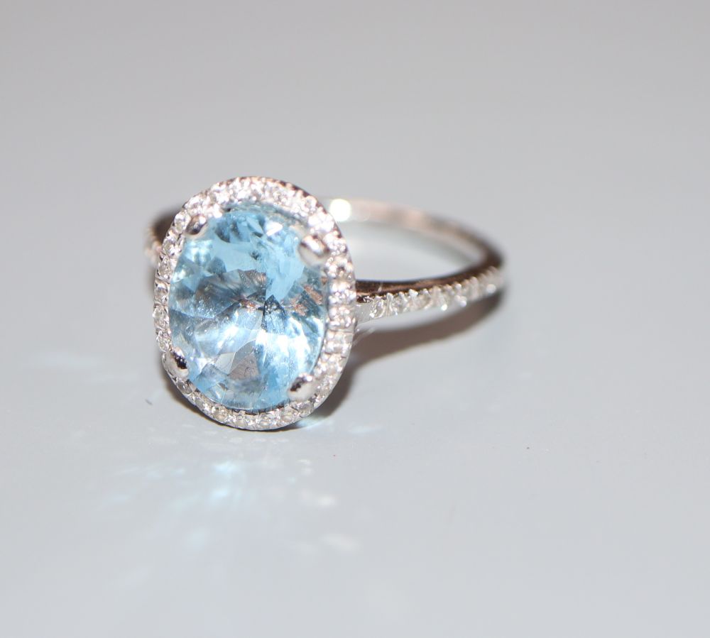 A modern aquamarine and diamond set oval dress ring, 18ct white gold setting, size J/K, gross 3.5 grams.